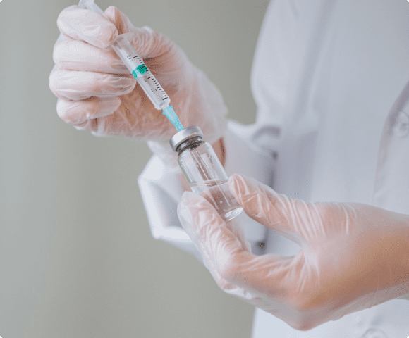 Врач набирает лекарство в шприц из ампулы